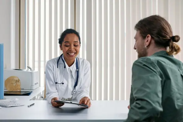 A doctor reviewing notes with a patient during a consultation
